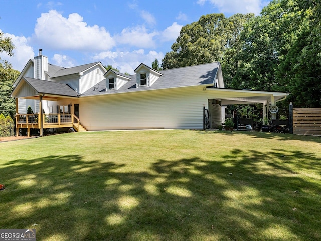 rear view of property featuring a deck, a carport, and a lawn