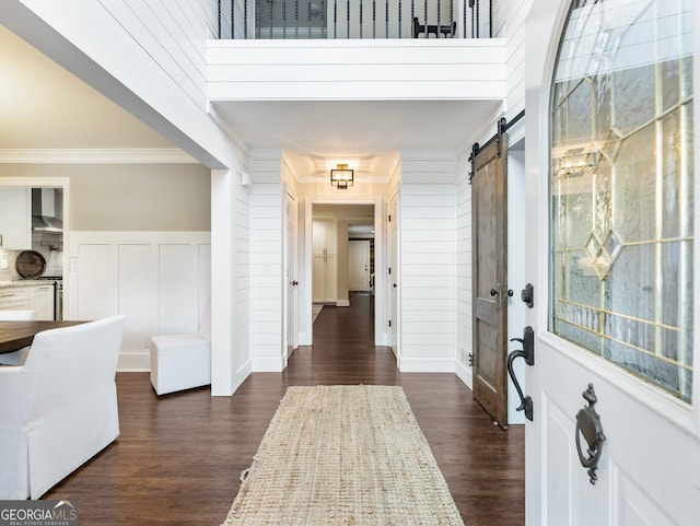 foyer entrance with crown molding, a barn door, dark hardwood / wood-style floors, and a healthy amount of sunlight