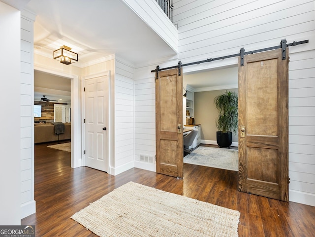 interior space featuring a barn door, dark wood-type flooring, visible vents, and crown molding