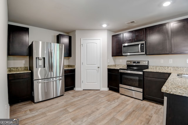 kitchen with appliances with stainless steel finishes, light wood-type flooring, dark brown cabinetry, and sink