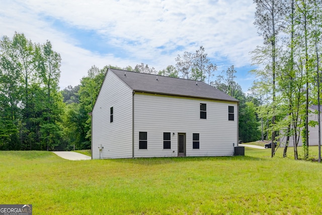 rear view of house featuring a lawn and cooling unit