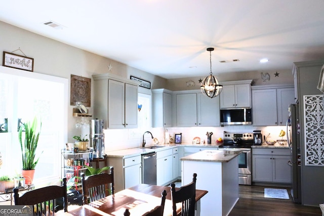 kitchen featuring a center island, sink, hanging light fixtures, gray cabinets, and stainless steel appliances