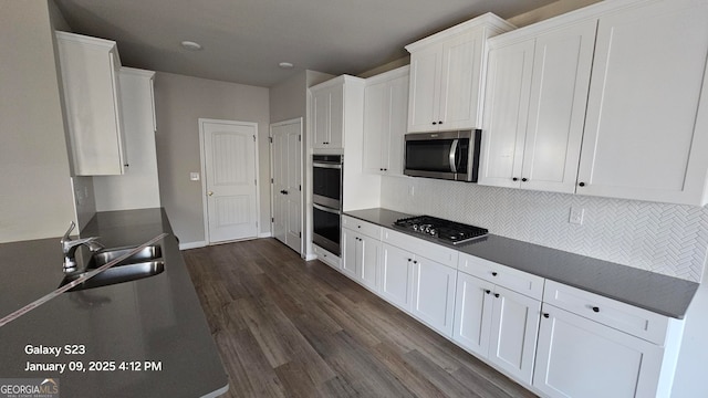 kitchen with decorative backsplash, stainless steel appliances, dark wood-type flooring, sink, and white cabinets