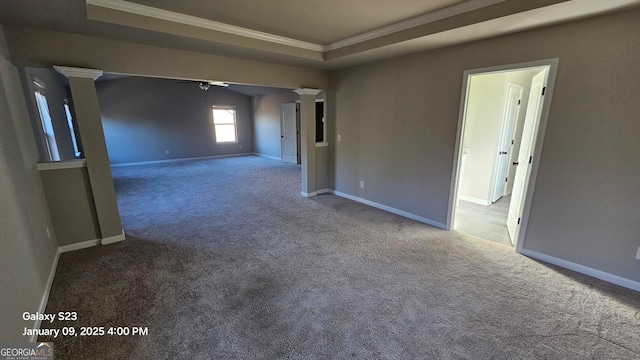 carpeted spare room with a tray ceiling, ornate columns, ceiling fan, and ornamental molding