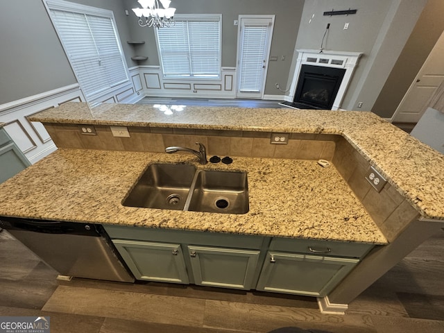 kitchen with dishwasher, sink, hanging light fixtures, green cabinetry, and light stone counters