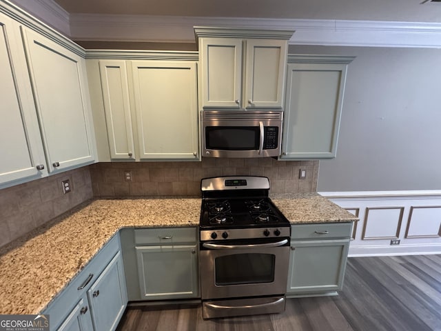 kitchen featuring tasteful backsplash, light stone countertops, stainless steel appliances, and ornamental molding