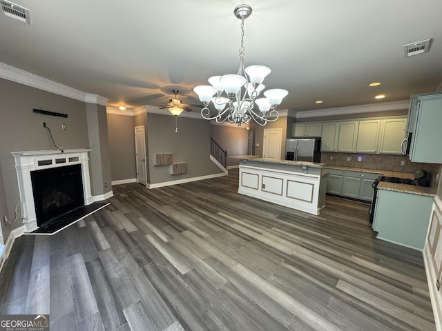 kitchen with tasteful backsplash, decorative light fixtures, a center island with sink, crown molding, and stainless steel appliances