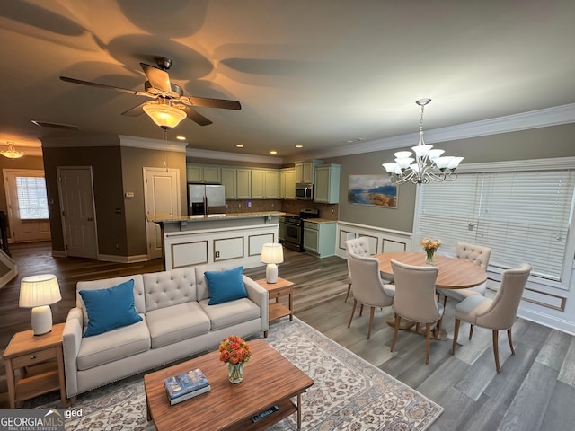 living room with ceiling fan with notable chandelier, hardwood / wood-style flooring, and crown molding