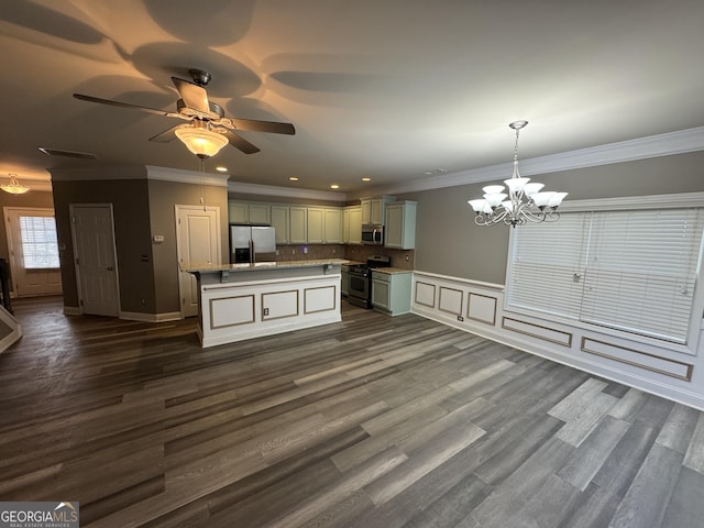 kitchen featuring pendant lighting, a kitchen island, appliances with stainless steel finishes, ornamental molding, and ceiling fan with notable chandelier