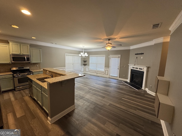 kitchen featuring ceiling fan with notable chandelier, stainless steel appliances, sink, backsplash, and a center island with sink