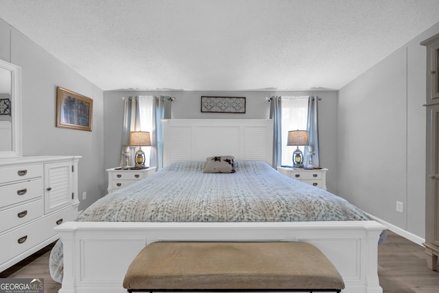 bedroom with a textured ceiling and dark hardwood / wood-style floors