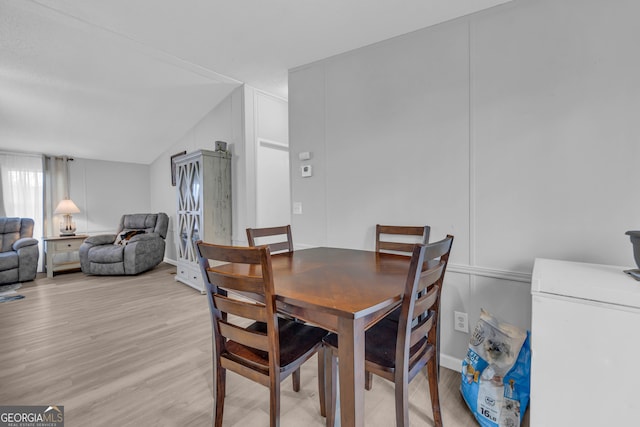 dining area with vaulted ceiling and light hardwood / wood-style flooring