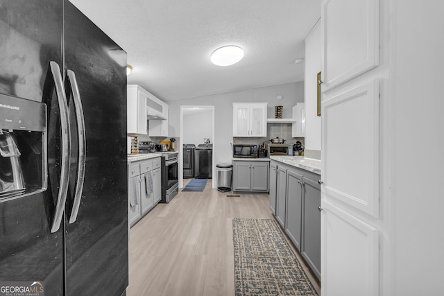 kitchen featuring lofted ceiling, black refrigerator with ice dispenser, light hardwood / wood-style flooring, electric range, and white cabinetry