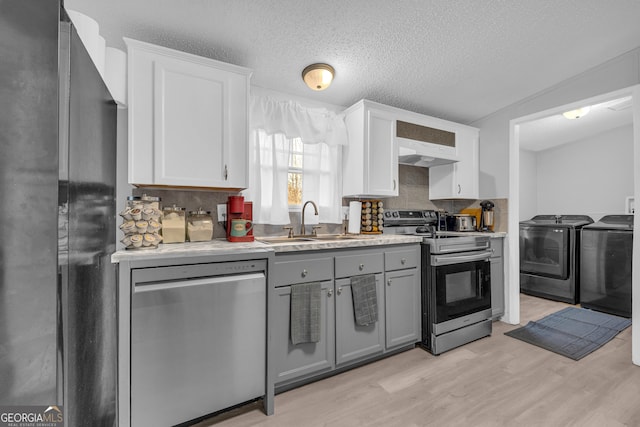 kitchen with sink, gray cabinets, washer and clothes dryer, white cabinets, and appliances with stainless steel finishes