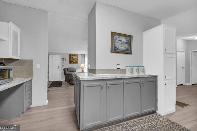 kitchen with gray cabinetry, backsplash, and light hardwood / wood-style flooring