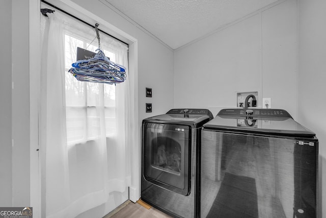 washroom featuring washing machine and dryer, light hardwood / wood-style floors, and a textured ceiling