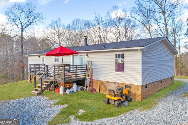 rear view of property featuring a wooden deck and a lawn