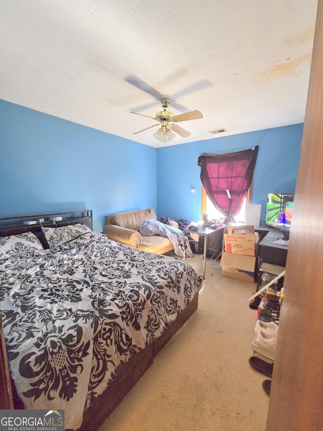 carpeted bedroom with ceiling fan and a textured ceiling