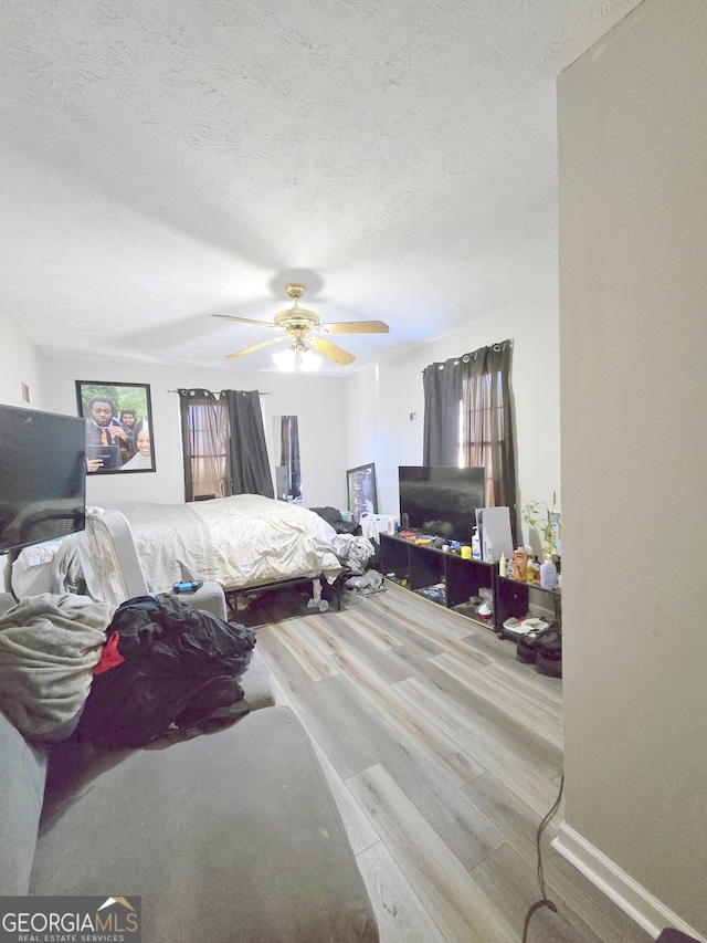 bedroom featuring ceiling fan, a textured ceiling, and light wood-type flooring