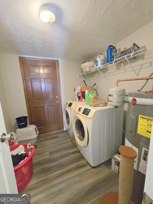 washroom with washer and dryer, dark hardwood / wood-style flooring, electric water heater, and a textured ceiling