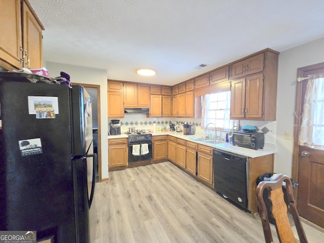 kitchen with light wood-type flooring, decorative backsplash, sink, and black appliances