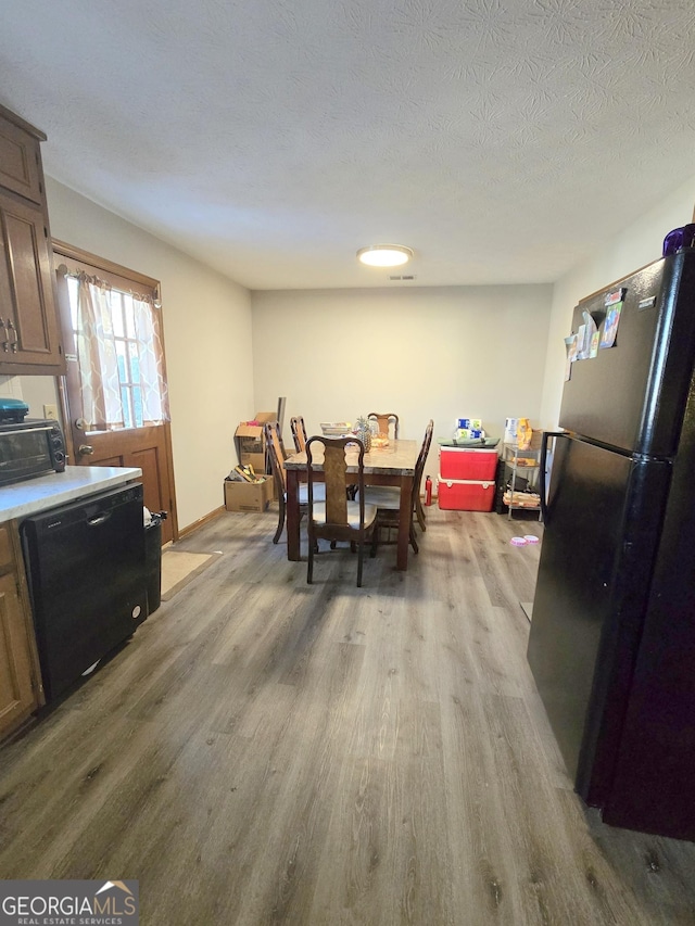 dining area featuring light hardwood / wood-style flooring and a textured ceiling