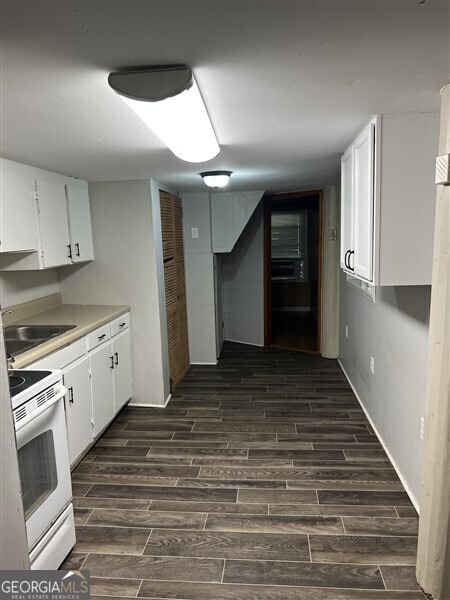 kitchen with sink, white cabinets, dark hardwood / wood-style floors, and white range with electric cooktop