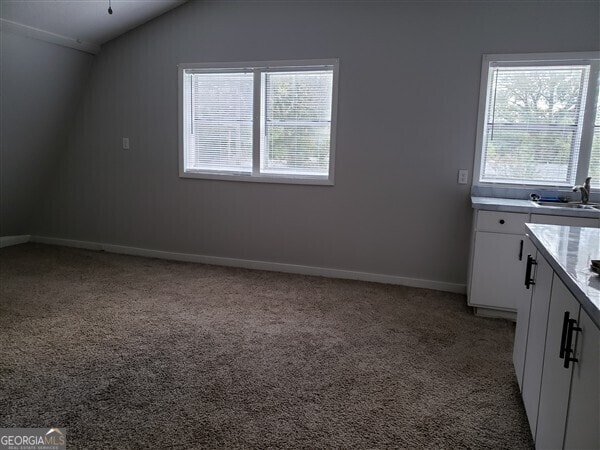 interior space featuring light colored carpet, sink, and lofted ceiling