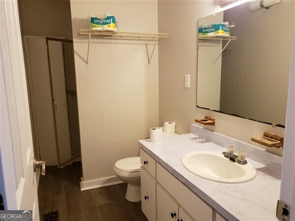 bathroom with hardwood / wood-style flooring, toilet, and vanity