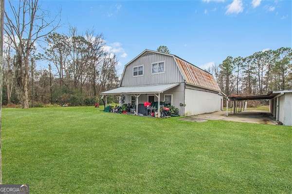 rear view of house featuring a carport and a lawn