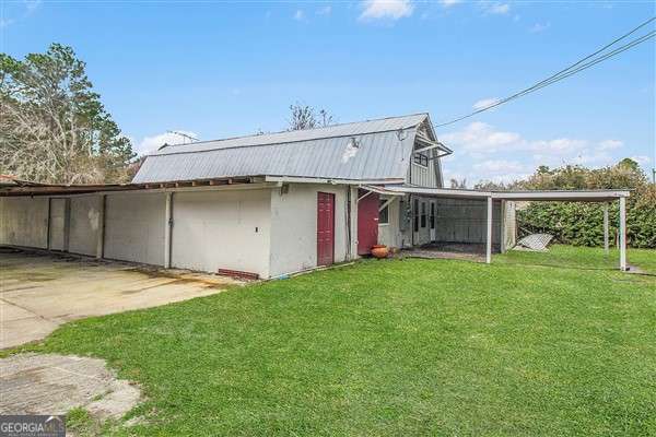 back of property featuring a lawn and a carport