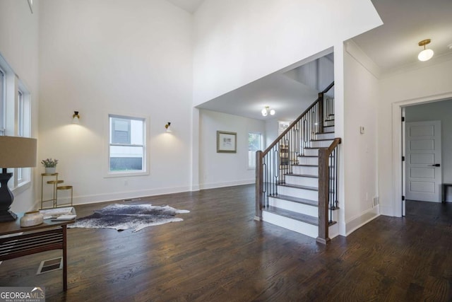 living room featuring crown molding, a high ceiling, and dark wood-type flooring