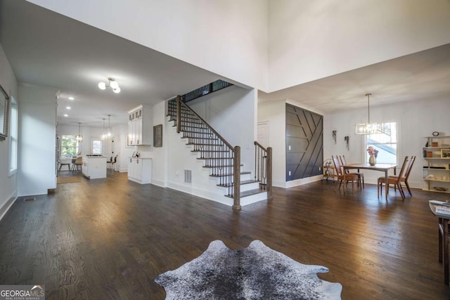 living room with a notable chandelier, plenty of natural light, and dark wood-type flooring