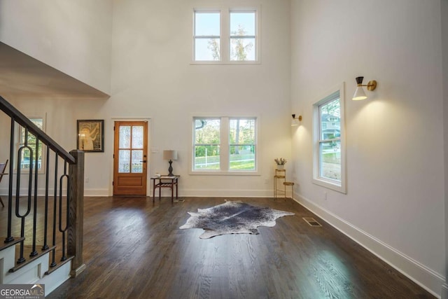 entrance foyer with a towering ceiling and dark wood-type flooring