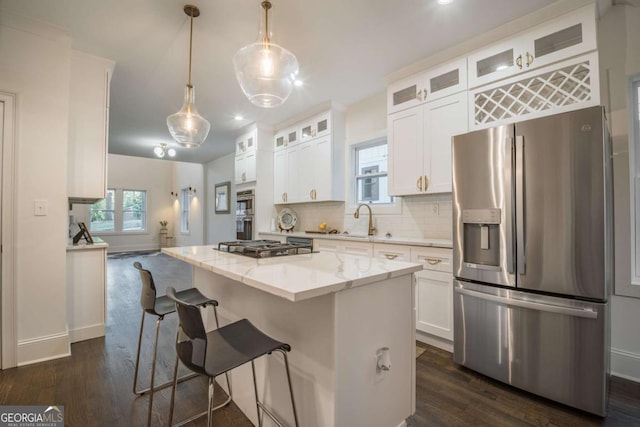 kitchen with white cabinets, appliances with stainless steel finishes, a kitchen island, and pendant lighting