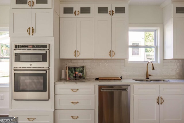 kitchen featuring tasteful backsplash, white cabinetry, sink, and appliances with stainless steel finishes