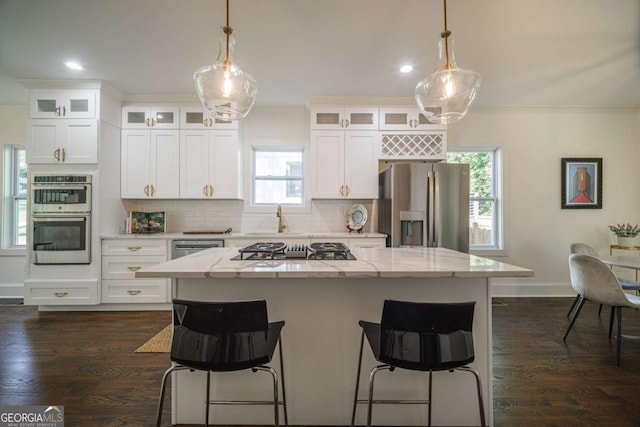 kitchen with white cabinetry, a center island, decorative light fixtures, and appliances with stainless steel finishes