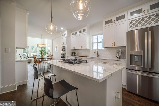 kitchen featuring decorative light fixtures, a kitchen island, white cabinetry, and appliances with stainless steel finishes