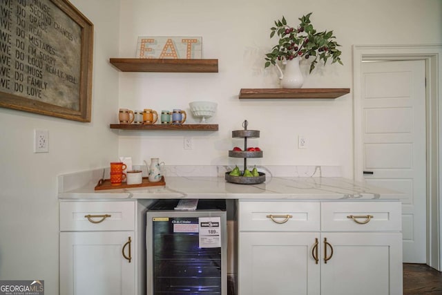 bar with white cabinets, light stone counters, and beverage cooler