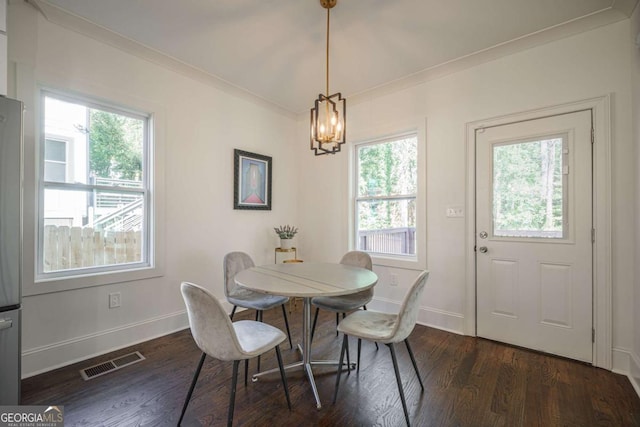 dining space with plenty of natural light, an inviting chandelier, dark wood-type flooring, and ornamental molding