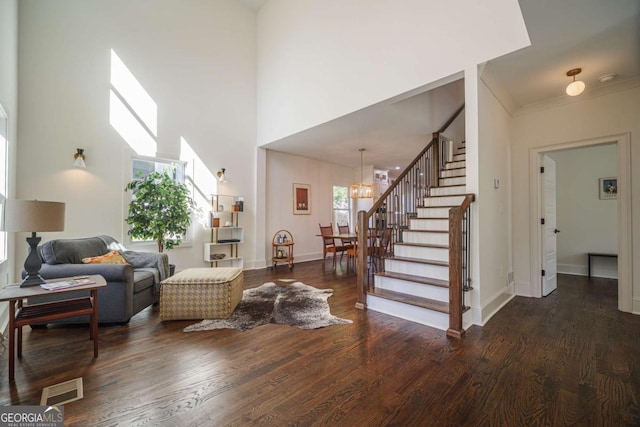 living room with dark hardwood / wood-style flooring, crown molding, and a notable chandelier