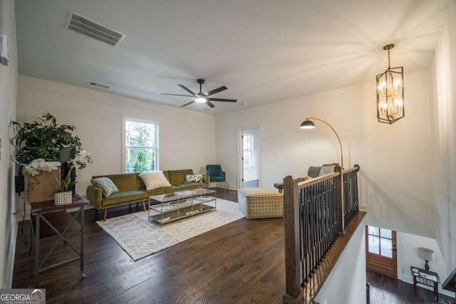 living room with ceiling fan with notable chandelier and dark wood-type flooring