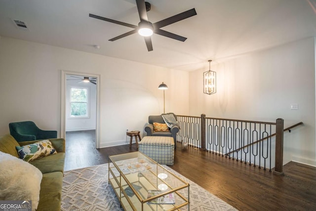 living room with ceiling fan with notable chandelier and dark wood-type flooring