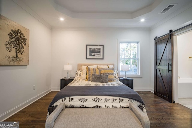 bedroom with dark hardwood / wood-style flooring, a barn door, and a raised ceiling