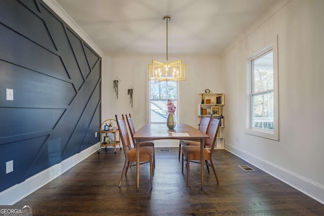 dining space with dark hardwood / wood-style flooring, an inviting chandelier, and ornamental molding