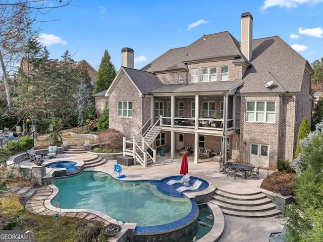 rear view of house featuring a patio and a pool with hot tub