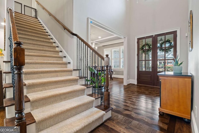 entrance foyer with french doors, dark parquet floors, and a high ceiling