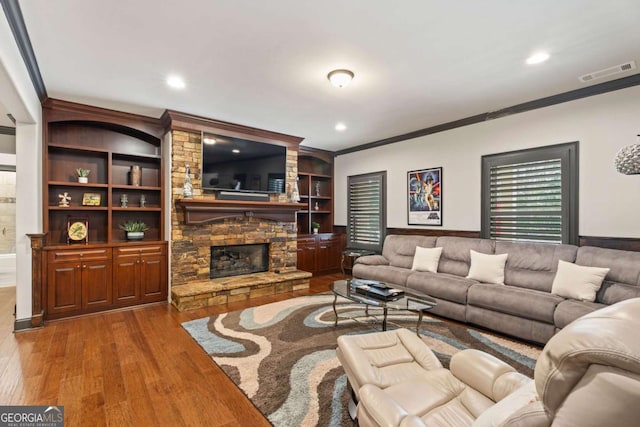 living room with a fireplace, wood-type flooring, built in features, and ornamental molding