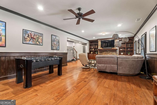 living room with hardwood / wood-style flooring, ceiling fan, built in features, and crown molding