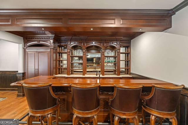 bar with hardwood / wood-style floors, butcher block countertops, and crown molding